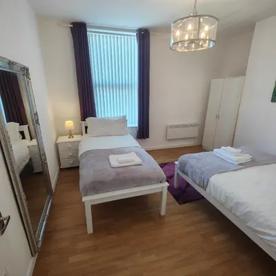 a bedroom with two beds and a mirror at Home from home - 2 bedroom apartment in Liverpool