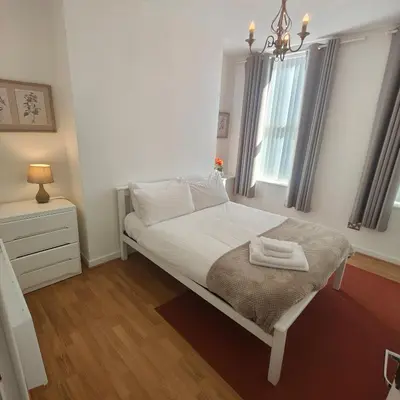 a bedroom with a bed with white sheets and a window at Home from home - 2 bedroom apartment in Liverpool