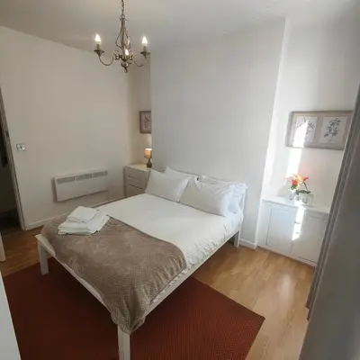 a bedroom with a bed with white sheets and a window at Home from home - 2 bedroom apartment in Liverpool