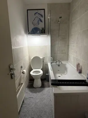 a bathroom with a toilet and a tub and a sink at City Apartment in Litherland