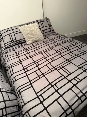 a black and white bed with a pillow on it at City Apartment in Litherland
