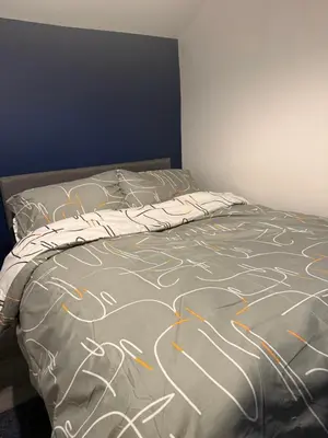 a bed with a bedspread with drawings on it at City Apartment in Litherland