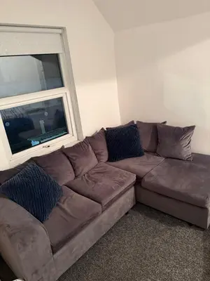 a brown couch in a living room with a window at City Apartment in Litherland