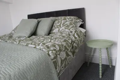a bedroom with a bed and a green table at Whole home Aintree Racecourse in Fazakerley