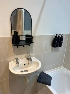 a bathroom with a sink and a mirror and a tub at Whole home Aintree Racecourse in Fazakerley