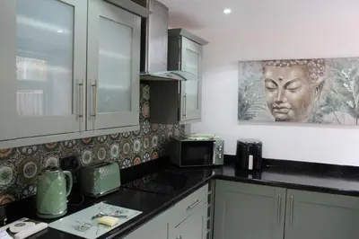 a kitchen with white cabinets and a picture of a head on the wall at Whole home Aintree Racecourse in Fazakerley
