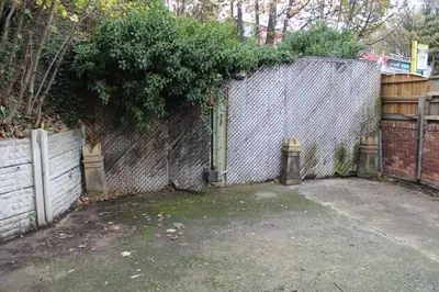 a chain link fence with a gate and a fence with a tree at Whole home Aintree Racecourse in Fazakerley