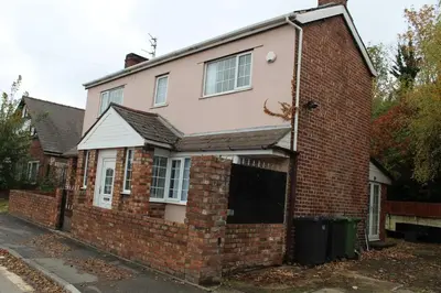 a brick house with a gate in front of it at Whole home Aintree Racecourse in Fazakerley