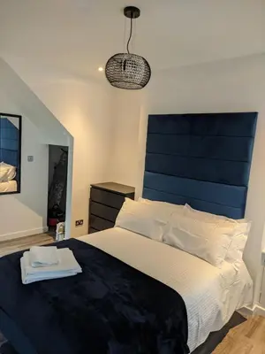 a bedroom with a large bed with a blue headboard at Dream101, Luxury 2 Bedroom apartment - free parking in Liverpool
