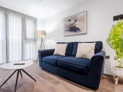 a living room with a blue couch and a table at Pass the Keys Luxury Flat with River Views. 1 Bed. Sleeps 4 in Liverpool