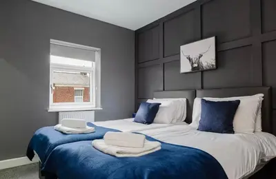 a bedroom with two beds with blue sheets and a window at Norris Stays - Sleeps 7 by M55 in Preston