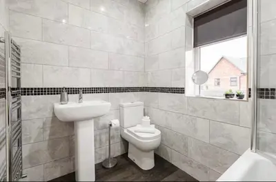 a bathroom with a toilet and a sink and a window at Norris Stays - Sleeps 7 by M55 in Preston