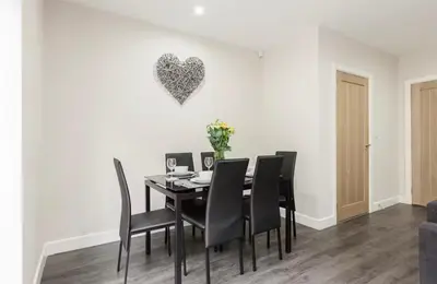 a dining room table with black chairs and a heart on the wall at Norris Stays - Sleeps 7 by M55 in Preston