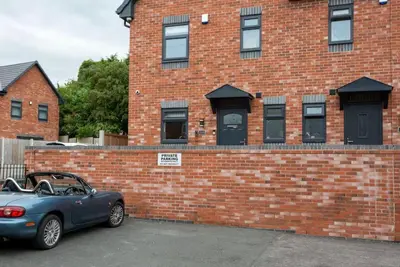 a blue car parked in front of a brick building at Norris Stays - Sleeps 7 by M55 in Preston