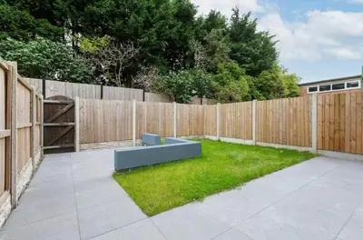 a backyard with a fence and a bench in the grass at Norris Stays - Sleeps 7 by M55 in Preston