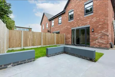 a backyard with a bench in front of a brick building at Norris Stays - Sleeps 7 by M55 in Preston