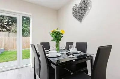 a dining room with a table with chairs and a vase of flowers at Norris Stays - Sleeps 7 by M55 in Preston