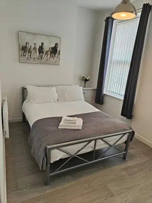 a bedroom with a bed with a bench next to a window at Home sweet Home, 2 bedrooms apartment in Liverpool
