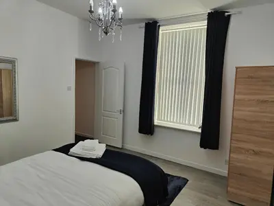 a bedroom with a bed and a window and a chandelier at Home sweet Home, 2 bedrooms apartment in Liverpool