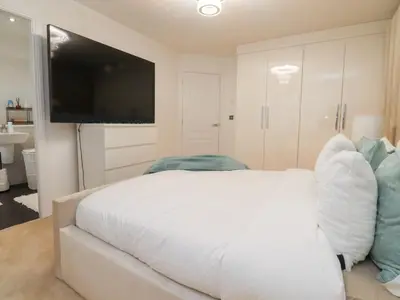 a bedroom with a white bed and a flat screen tv at Mellings Place in Carnforth