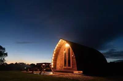 a small wooden cabin with a window at night at Kidsnape Farm by Wigwam Holidays in Goosnargh