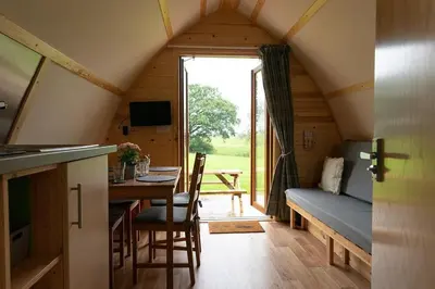 a room with a table and a couch in a cabin at Kidsnape Farm by Wigwam Holidays in Goosnargh