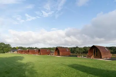 a group of barns in a grass field at Kidsnape Farm by Wigwam Holidays in Goosnargh