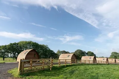 a group of barns in a field with a fence at Kidsnape Farm by Wigwam Holidays in Goosnargh