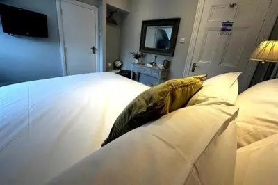a bedroom with a white bed and a television at Station lounge in Clitheroe