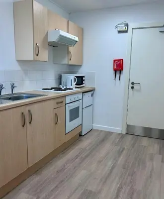 a kitchen with wooden cabinets and a sink and a refrigerator at For Students Only Myrtle Court in Liverpool in Liverpool