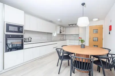 a kitchen with white cabinets and a wooden table and chairs at For Students Only The Railyard in Liverpool in Liverpool