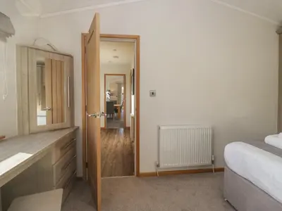 a bedroom with a bed and a dresser and a mirror at Bluebell Lodge in Carnforth