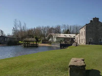 a building next to a river with a gazebo at Bluebell Lodge in Carnforth