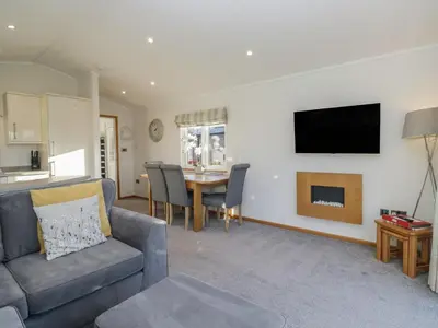 a living room with a couch and a tv on a wall at Bluebell Lodge in Carnforth
