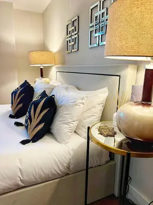 a bedroom with a bed with white pillows and a table at Central, Stylish 2BR Flat Sleeps 6 with Parking! in Liverpool