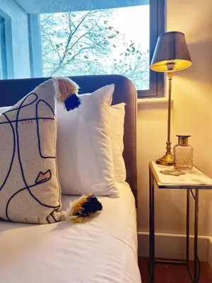 a bed with a pillow and a lamp and a window at Central, Stylish 2BR Flat Sleeps 6 with Parking! in Liverpool