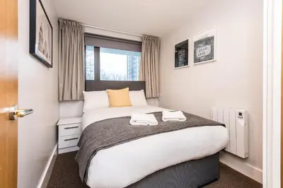 a bedroom with a large bed with two towels on it at Modern 2BR Flat, City Centre, Balcony & Parking! in Liverpool