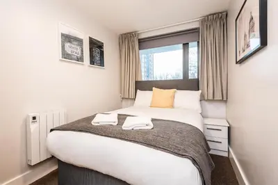 a bedroom with a large bed with two towels on it at Modern 2BR Flat, City Centre, Balcony & Parking! in Liverpool