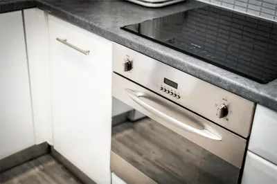 a kitchen with white cabinets and a stove at Modern 2BR Flat, City Centre, Balcony & Parking! in Liverpool