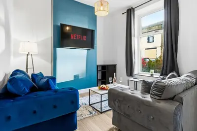 a living room with a couch and a blue wall at Spacious 3B Home, ideal for contractors & family! in Clayton le Moors