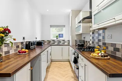 a kitchen with white cabinets and wooden counter tops at Spacious 3B Home, ideal for contractors & family! in Clayton le Moors