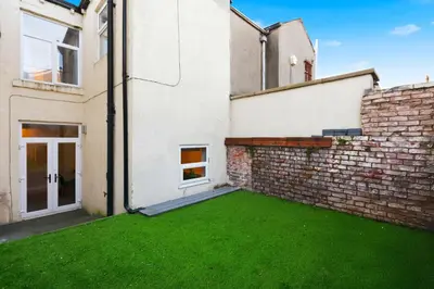 an empty backyard with a brick wall and green grass at Spacious 3B Home, ideal for contractors & family! in Clayton le Moors
