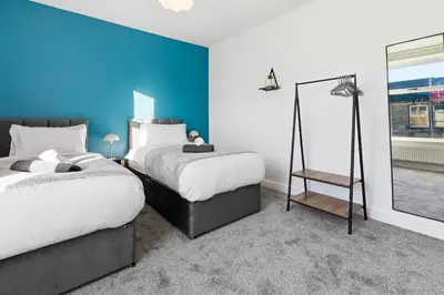 a bedroom with two beds and a blue wall at Spacious 3B Home, ideal for contractors & family! in Clayton le Moors
