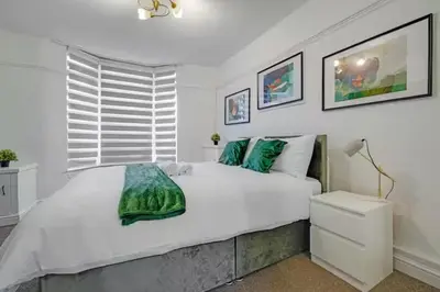 a white bedroom with a large bed and a window at Home in Anfield in Liverpool
