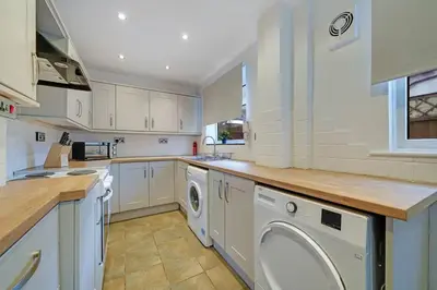 a kitchen with white cabinets and a washer and dryer at Home in Anfield in Liverpool