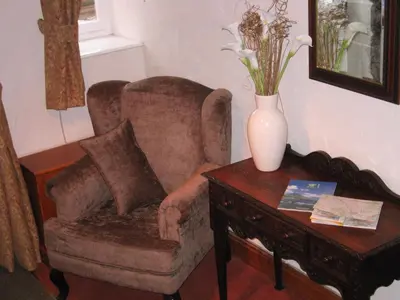 a living room with a chair and a vase on a table at Rock Cottage - Log burners and jacuzzi bath in Lindale