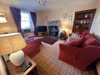 a living room with a red couch and a fireplace at Rock Cottage - Log burners and jacuzzi bath in Lindale