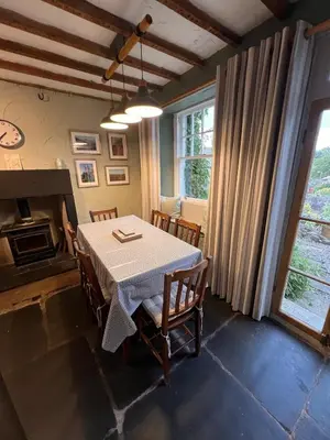 a dining room with a table and chairs and a fireplace at Rock Cottage - Log burners and jacuzzi bath in Lindale