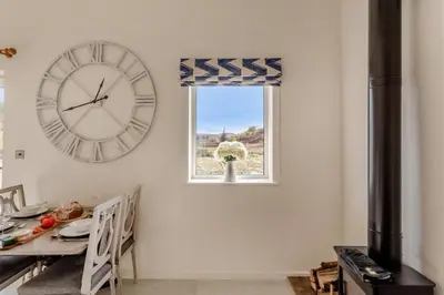 a clock on a wall next to a table and a window at 2 Bed in Dunsop Bridge oc-w33524 in Newton