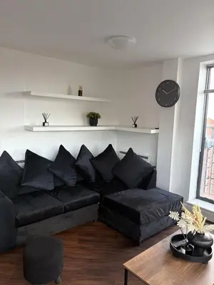 a living room with a black couch and a table at Liverpool City Centre - Skyline Apartment in Liverpool